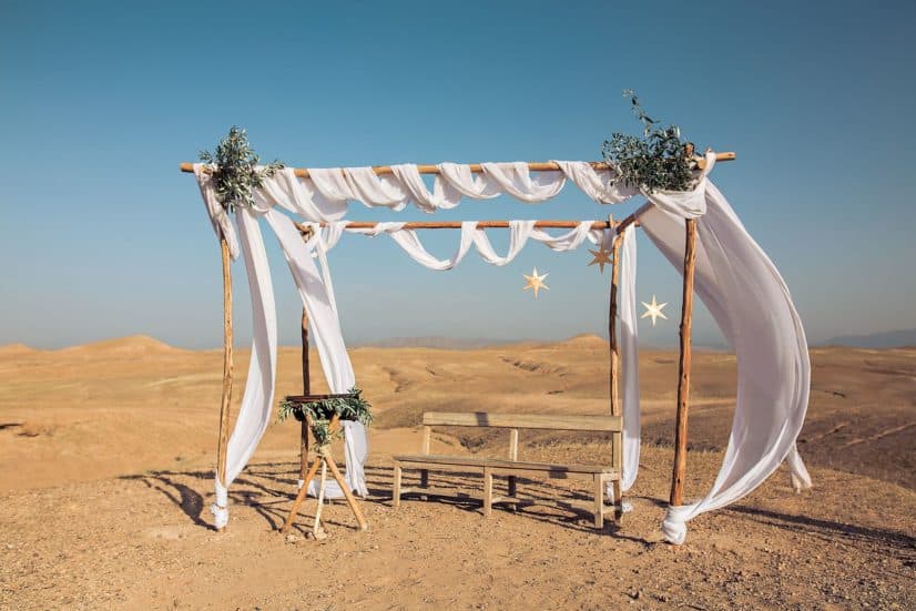 Wedding ceremony arch draped in white fabric in the Agafay desert